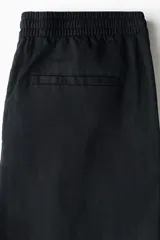 Pantalón negro de corte regular, confeccionado en una mezcla vaporosa de lino y algodón. Presenta cintura con elástico revestido y cordón de ajuste, cierre con botón y bragueta, bolsillos laterales y bolsillos traseros insertados.