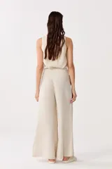 Pantalón de lino color beige, de cintura alta con elástico, bolsillos laterales y corte palazzo.