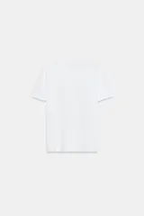Camiseta de algodón con cuello redondo y manga corta. Presenta un diseño estampado frontal con efecto metalizado plateado sobre fondo rectangular.