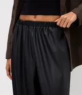 Pantalón aladín de poliuretano color negro, de corte ancho con diseño abullonado y botamangas elásticas ajustadas, con cintura elástica.