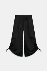 Pantalón culotte negro de tiro medio con cintura elástica, bolsillos laterales ocultos y bajo ajustable con cordones fruncidos.