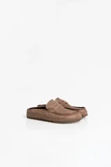 Zuecos tipo mule estilo mocasín, confeccionados en material símil gamuza color chocolate, con punta redondeada, costuras decorativas y tira frontal estilo penny.