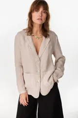 Blazer de lino italiano color beige, de botonadura sencilla, solapas clásicas, bolsillos de parche y detalle de puños tableados.