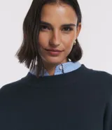Suéter de tejido de punto color verde oscuro, de corte clásico con cuello redondo y manga larga.