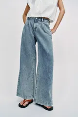 Jeans de tiro medio con pernera ancha, diseño wide leg y pinzas delanteras. Cuenta con bolsillos frontales, bolsillos traseros de plastrón y cierre frontal con cremallera y botón.