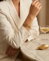 Pulsera de acero con baño de oro, compuesta por una malla metálica ajustable tipo cinturón y un dije central en forma de corazón con la palabra 'Mamá' calada en su interior.