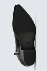 Bota de media caña en color negro, con diseño de arnés que incluye tiras, argollas metálicas y tachas decorativas alrededor del tobillo. Presenta punta fina y tacón cuadrado.