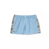 Short de baño Lacoste color celeste, con cintura elástica y cordón ajustable. Presenta bandas laterales con estampado de la marca y el logo del cocodrilo bordado en la pierna izquierda.