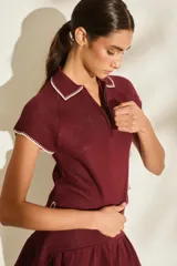 Top de punto color marrón, con cuello polo y cierre frontal parcial, manga corta y detalles de costuras a contratono en los bordes.