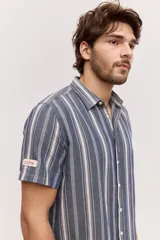 Camisa de manga corta color azul con diseño a rayas verticales, cuello clásico y cierre frontal de botones.