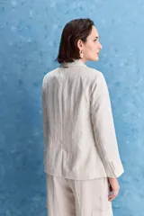 Blazer color beige claro, de corte clásico con solapa, cierre de un botón y bolsillos delanteros de vivo.