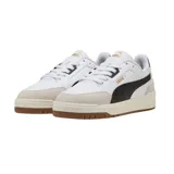Championes Puma modelo Shuffle Downtown OG, de diseño urbano con base blanca, detalles en negro y suela de goma color caramelo. Presentan refuerzos en gamuza gris en la puntera y el talón, con el logo de la marca en dorado.