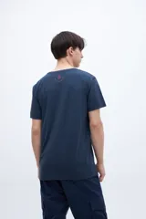 Remera de algodón color azul marino con cuello redondo y mangas cortas. Presenta un estampado gráfico central con texto en tonos azul claro, rojo y amarillo, incluyendo una pequeña estrella.