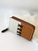 Billetera pequeña de cuero color camel y crudo, con cierre metálico y detalle de cruces bordadas en hilo negro.