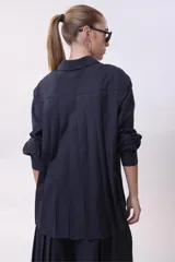 Camisa blanca de corte oversize, con cuello clásico y mangas largas con puños abotonados.