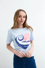 Remera celeste de manga corta y cuello redondo, con estampa frontal en forma de corazón que combina una ola, un atardecer y la frase "Life is Good".
