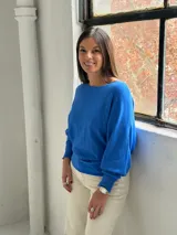 Sweater de punto color azul vibrante, con diseño de textura acanalada vertical en el frente, cuello redondo y mangas murciélago con puños ajustados.