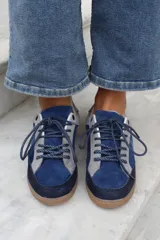 Championes de estilo urbano en combinación de tonos marrones y crema, confeccionados en gamuza y cuero. Presentan cordones jaspeados, suela de goma y detalle de logo bordado en el lateral.