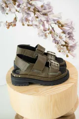Sandalias negras de cuero con diseño de plataforma dentada, tiras ajustables con hebillas metálicas y detalle de tachas plateadas en el lateral de la suela.