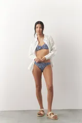 Top de bikini con estampado floral en tonos azules y blancos, con corte en el centro del busto y tirantes finos regulables.
