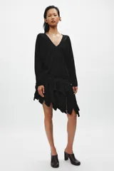 Jersey de punto fino negro con escote en V pronunciado, mangas largas y corte holgado con bajo asimétrico, más largo en la parte trasera.