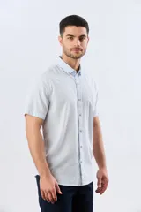 Camisa de manga corta confeccionada en mezcla de lino y algodón, con diseño de rayas verticales en tonos celeste y blanco. Cuenta con cuello camisero, botonadura frontal y bordado sutil en el pecho.