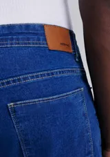 Pantalón de jean de corte slim, color azul, con cierre de botón y cremallera, y bolsillos laterales y traseros.