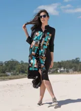 Vestido camisero largo negro de viscosa con diseño pintado a mano en el frente en tonos dorado, cobre, turquesa y celeste, de manga larga, cuello mao y cierre frontal con botones.
