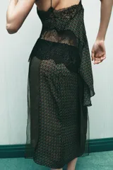 Falda tipo pareo de tiro bajo con estampado geométrico en tonos verdes y naranjas. Confeccionada en viscosa 100%, tiene un bajo asimétrico y cierre lateral con cremallera oculta.