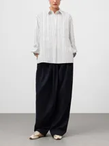 Camisa de corte oversize confeccionada en algodón orgánico, con estampado de rayas verticales. Presenta cuello solapa, manga larga con puños, bolsillo en el pecho y cierre frontal oculto por tapeta.