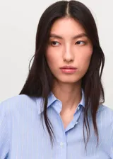 Camisa de rayas celestes y blancas, de manga larga con puños abotonados, corte recto, cuello camisero y cierre delantero con botones.