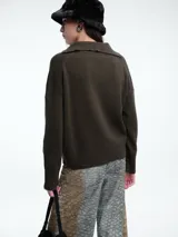 Sweater de punto color verde oliva, con cuello polo abierto en V, manga larga con hombros caídos y terminaciones acanaladas en puños y ruedo.