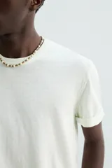 Camiseta relaxed fit de punto ligero color blanco hueso, con cuello redondo y manga corta. Acabados en rib.