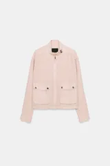 Chaqueta Zara de corte holgado con efecto lavado, cuello subido, cierre frontal con cremallera y botones a presión. Presenta dos bolsillos de plastrón con solapa y botones en el delantero, mangas largas y bajo ajustable con cordones.