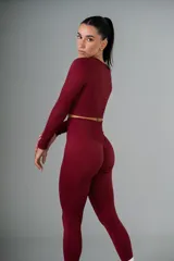 Conjunto deportivo color borgoña, compuesto por calzas largas de tiro alto y top crop de manga larga. Ambos de tejido acanalado.