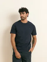 Remera básica de algodón color beige, de manga corta, con cuello redondo y un pequeño detalle bordado en el pecho.