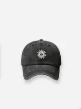 Gorra tipo baseball de color negro con efecto lavado, con bordado frontal de un sol con rostro en color blanco.