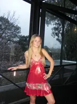 Vestido corto de tela metalizada en tono fucsia con reflejos dorados, con escote en V, diseño de top con triángulos, aberturas laterales en la cintura y doble volado irregular en el ruedo.