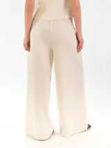 Pantalón de lino color beige, de corte ancho y relajado, con pretina elástica y cierre de botón.
