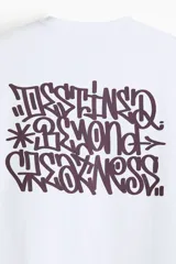 Remera blanca de punto de algodón de peso medio, con cuello redondo ribeteado y hombros caídos. Presenta un pequeño estampado minimalista de un emoji con la boca recta en el pecho.