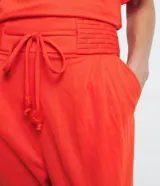 Pantalón jogger color naranja, de tiro medio, con cintura elastizada, lazo ajustable, pliegues delanteros y bolsillos laterales.