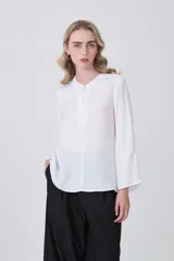 Blusa de poliéster color blanco, con cuello redondo, cierre frontal parcial con botones y mangas tres cuartos.