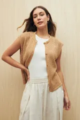 Chaleco color beige de tejido calado, sin mangas, con botones al frente y diseño abierto.