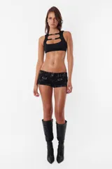 Microshort de gabardina de tiro bajo y corte slim fit. Presenta costuras en contraste color rojo, cierre metálico frontal y presillas largas en la cintura. La prenda cuenta con un proceso de sobreteñido y lavado artesanal que le otorga un aspecto desgastado único.