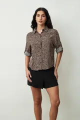 Camisa de manga tres cuartos con estampado de leopardo en tonos beige y negro, cuello camisero y botones frontales.
