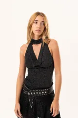 Top sin mangas de tejido lurex negro con acabado brillante, cuello halter y escote cruzado.
