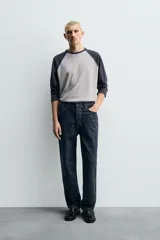 Camiseta de corte relajado con diseño color block, cuerpo en gris melange y mangas largas raglán en color azul marino. Presenta cuello redondo al tono de las mangas y bajo con acabado irregular.