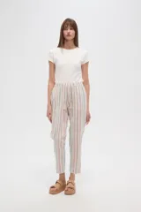 Pantalón tipo babucha de corte recto y holgado, con estampado de rayas verticales en tonos beige, blanco y verde agua. Cuenta con cintura elástica con cordón ajustable y borlas decorativas en los extremos.