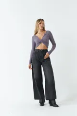 Top de manga larga en tejido rib negro, con escote en V profundo y detalle de nudo frontal que genera un efecto fruncido.