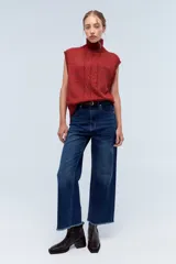 Chaleco de punto azul con cuello alto y diseño de trenzas.